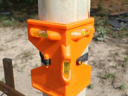 A orange post level with elastic strap is on the round wooden post.